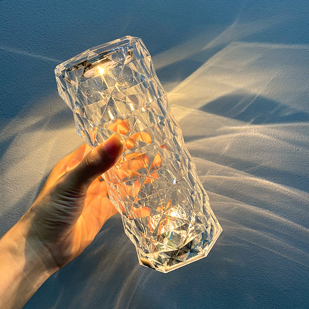 Hand holding a Crystal LED Touch Table Lamp with lights inside against a blue background